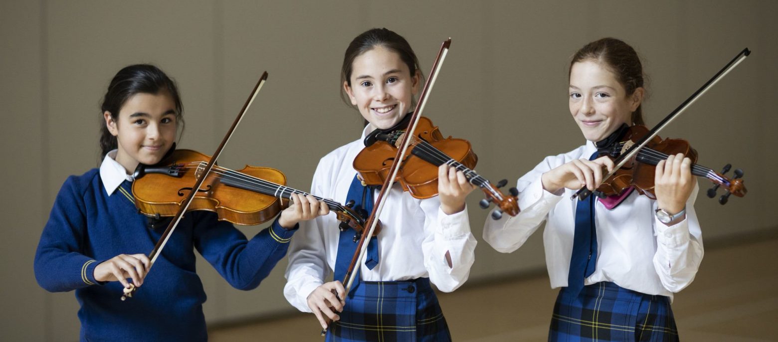 three girls holding violins