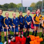 group of school girls in PE kits holding hockey sticks