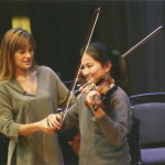 woman teaching girl to play violin