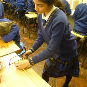 school girl cutting wood