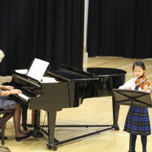 girl playing violin and woman playing the piano