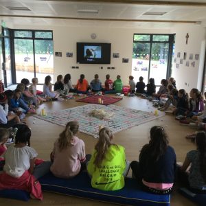 school children sitting in a circle watching tv