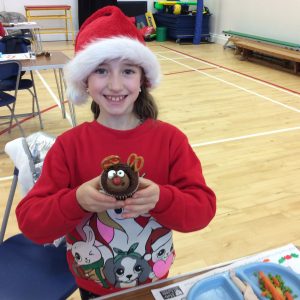 child holding a reindeer cupcake