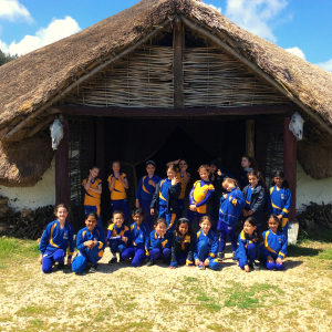 thatch house with students in the front