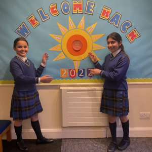 girls standing by a welcome sign