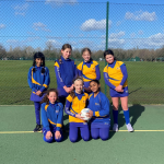 girls holding a football and standing with their other team members