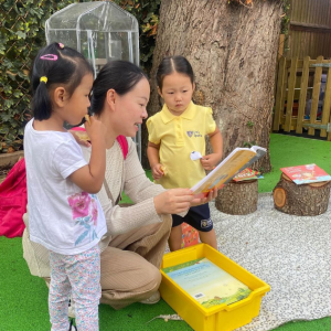 teacher reading a book to two pupils