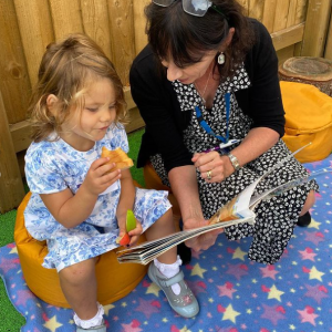 a girl eating while reading to her teacher