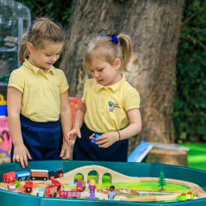 students playing with a wooden train track