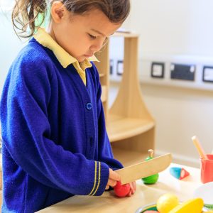 student cutting toy veg